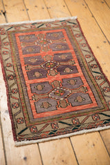 Distressed vintage Oushak rug showing brick red, violet geometric medallion, and floral border.
