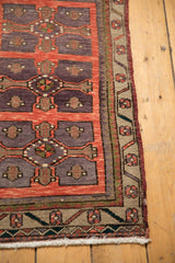 Distressed Oushak rug corner detail with brick red and violet floral border, sage accents.