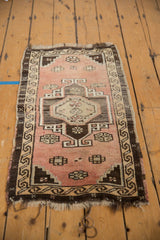 Distressed Oushak rug with faded blush field, dark brown geometric medallion, and tattered end.
