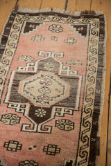 Distressed Oushak rug: blush field, charcoal medallion, floral motifs, running water border.