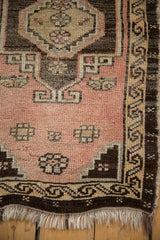 Distressed vintage Oushak rug corner, dusty blush field, running water border, tattered fringe.