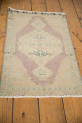 Distressed vintage Oushak rug corner with evenly worn beige and dusty mauve motifs.