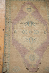 Distressed vintage Oushak rug detail with even wear, showing soft beige, mauve, and blue tones.