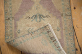 Folded corner of vintage distressed Oushak rug, showing worn pile, subtle colors, and woven foundation.
