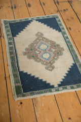 Distressed vintage Oushak rug pile, ivory field, navy stepped spandrel, green patterned border.