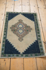 Vintage Oushak rug showing navy blue stepped corner, pale forest green border, and fringe.