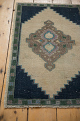 Distressed Oushak rug's navy stepped corner, pale green border, and fringe.
