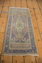 Distressed Oushak rug corner, showing lilac, mint, and sand meandering vine border.