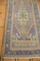 Angled view of distressed Oushak rug border with lilac floral vines and serrated medallion.