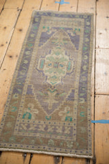 Distressed Oushak rug corner: lilac, sand, mint green meandering floral border with even wear.
