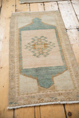 Distressed Oushak rug mat fringed end, showing worn texture and beige, blue-green.