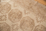 Distressed Ersari carpet's elephant footprint gul motif, showcasing even wear in tone-on-tone ivory and beige.