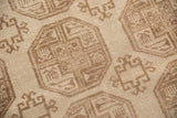 Close-up of distressed Ersari carpet pile showing ivory, beige elephant footprint gul motifs.