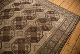 Distressed Ersari carpet corner featuring geometric guls in chocolate brown, antique ivory, and muted green.