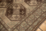 Vintage Ersari carpet close-up: distressed geometric guls, even wear in brown, ivory, copper green.
