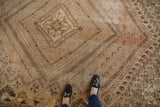 Overhead view of a distressed vintage Shiraz rug with worn pile and faded geometric patterns.