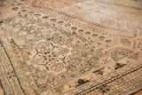 Distressed vintage Shiraz carpet with even wear, pale blush, sand, and charcoal tribal motifs.