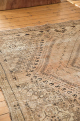 Distressed vintage Persian Shiraz carpet: worn charcoal geometric, floral patterns on blush, sand.