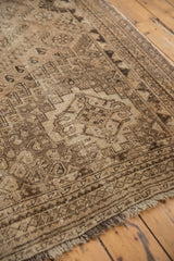 Textured distressed pile of vintage Shiraz carpet corner, revealing soft sand and charcoal tones.