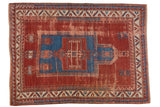 Antique Kazak rug with sapphire blue prayer niche on cherry red field and geometric patterns.