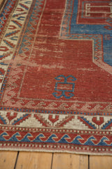 Cherry red antique Kazak border with sapphire blue wave motif, ivory serrated leaf, and visible wear.