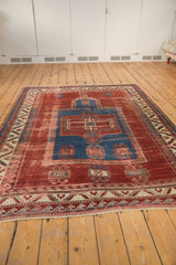 Antique Kazak rug lower border: serrated leaf and wave motifs on cherry red field with visible foundation.