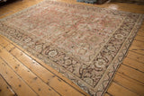 Distressed Mahal carpet corner, showing pale raspberry floral field, ornate charcoal border, and even wear.