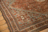 Distressed vintage Shiraz carpet corner spandrel showing inverted dusty blue-gray and chestnut patterns.