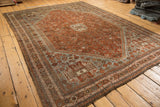 Distressed vintage Shiraz rug corner showing chestnut field, dusty slate gray spandrel, and visible wear.