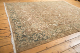 Distressed vintage Heriz carpet with ivory field, slate gray border, and floral motifs.