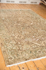 Distressed Heriz carpet corner, soft beige and blue-green floral motifs, worn texture.