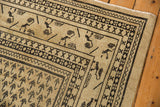 Distressed corner of vintage Mir Sarouk carpet, showing soft beige pile and dark patterned borders.