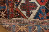 Woven edge and short fringe of a Baktiari carpet, showing geometric border in red, blue, ivory.