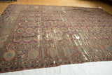 Wine red geometric elephant footprint gul motifs and intricate borders with scattered holes on an antique Turkmen rug.