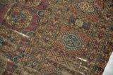Intricate geometric gul patterns in wine red, navy, ivory, displaying wear on antique Turkmen carpet.