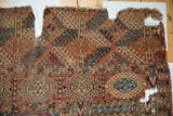 Geometric 'elephant footprint' gul motifs, terracotta, navy, and ivory, with visible holes and splits.