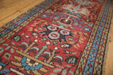 Heriz runner's cherry red field detailed with sky blue blossoms and patterned sand border.