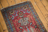 Vintage Heriz runner corner showing tattered fringe, cherry red field, and blue geometric border.