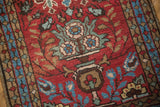 Close-up of Vintage Heriz rug's cherry red field, blue-green germinating plant motif, knot wear.
