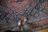 Cherry red and navy blue Joshegan carpet with intricate paneled lattice and aged surface texture.