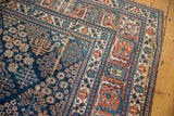 Distressed corner of a vintage Joshegan carpet with hard wear, splits, and paneled lattice design.