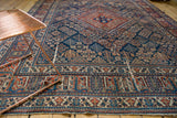 Vintage Joshegan carpet detail: ornate border patterns in cherry red, navy blue, and visible wear.