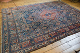 Intricate paneled border of vintage Joshegan carpet, showing navy blue, cherry red, and worn edge.