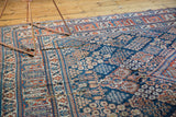 Vintage Joshegan carpet detail with a split in its intricate navy blue and cherry red pattern.