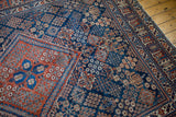 Distressed vintage Joshegan carpet, showing an intricate corner design in cherry red and navy.