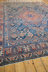 Worn fringe and intricate cherry red, navy blue border of the vintage Joshegan rug.