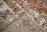 Corner of an antique Karaja rug folded back to show the hand-knotted weave and distressed pile.