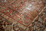 Distressed Mehrivan carpet detail showing faded brick red, beige, and charcoal geometric patterns with foundation wear.