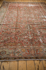 Close-up of a distressed Persian Mehrivan rug's geometric border, faded red, and grey tones.