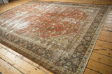 Distressed Mahal carpet displaying brick red floral motifs and textured, faded tones.